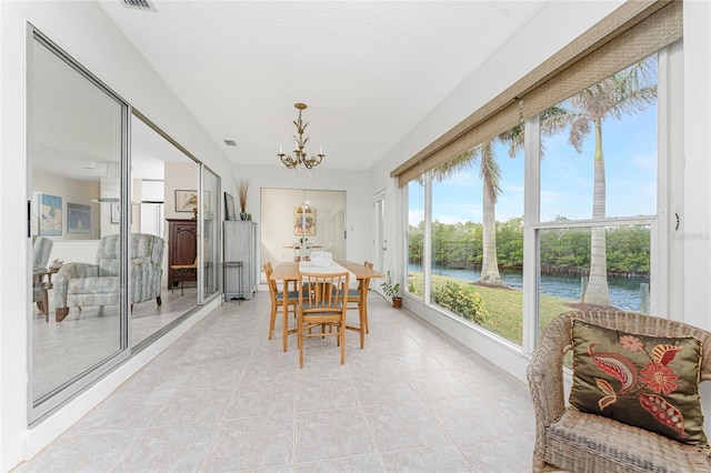 sunroom featuring a water view and a chandelier