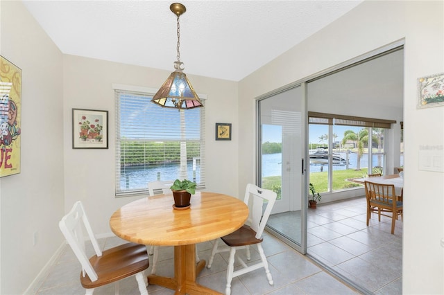 tiled dining space with a water view and a textured ceiling