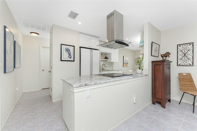 kitchen featuring white cabinets, island range hood, kitchen peninsula, and built in refrigerator