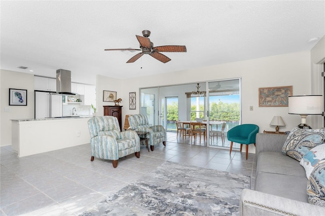 living room with ceiling fan, light tile patterned flooring, sink, and a textured ceiling