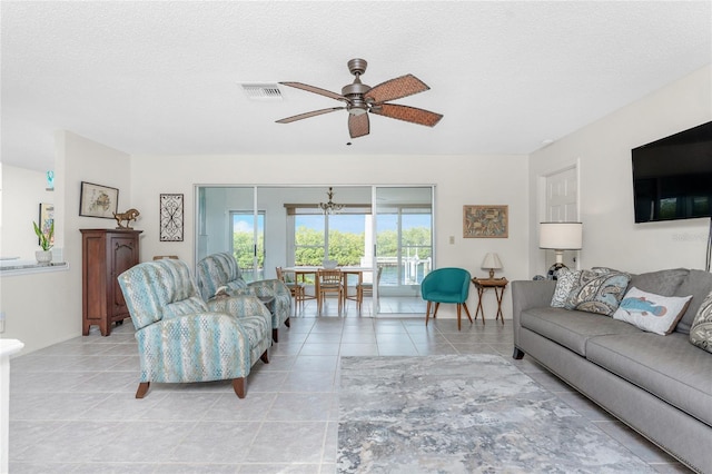 tiled living room with ceiling fan and a textured ceiling