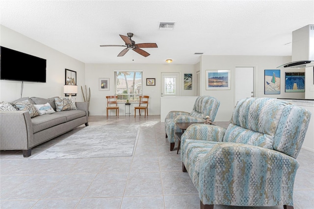 living room with ceiling fan, light tile patterned floors, and a textured ceiling