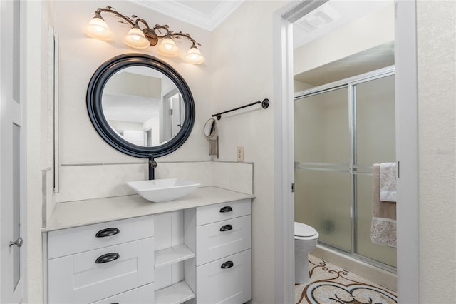 bathroom with vanity, toilet, a shower with shower door, and crown molding