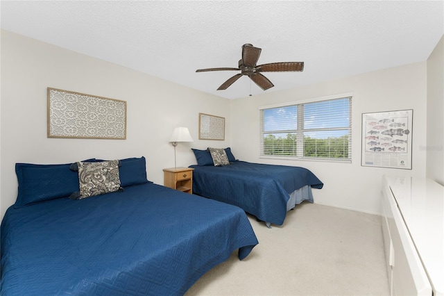 bedroom with ceiling fan, carpet floors, and a textured ceiling