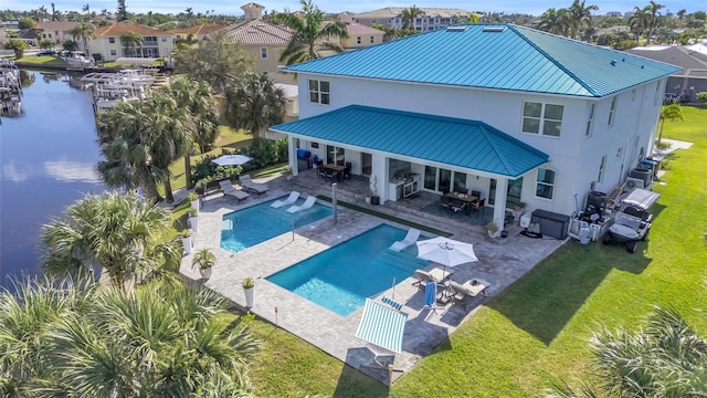 rear view of house with outdoor lounge area, a yard, a water view, and a patio