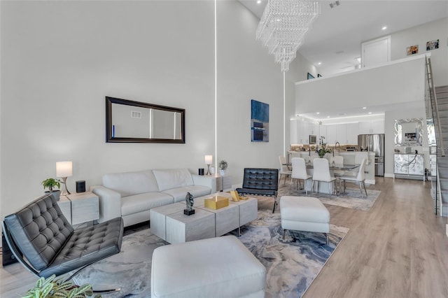 living room with a high ceiling, light hardwood / wood-style floors, and a notable chandelier