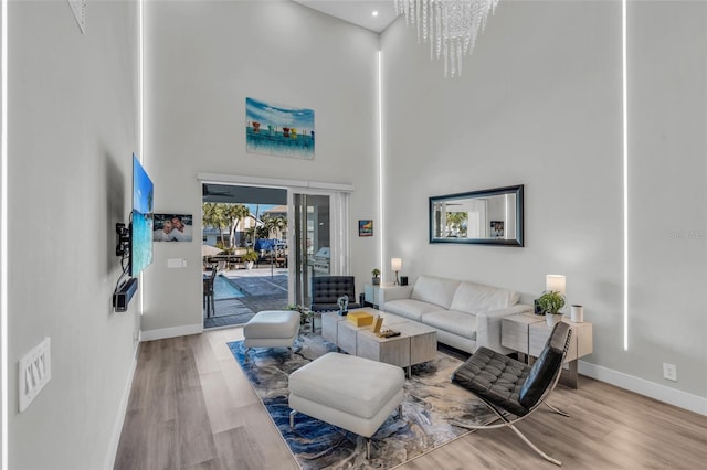 living room with a towering ceiling, hardwood / wood-style flooring, and a notable chandelier