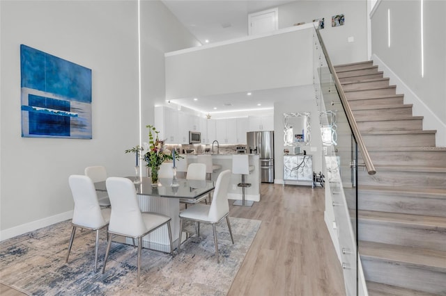 dining room featuring a towering ceiling, light hardwood / wood-style floors, and sink