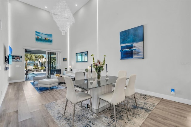 dining space with hardwood / wood-style floors, a high ceiling, and a chandelier