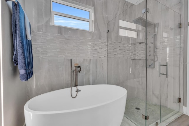 bathroom featuring shower with separate bathtub and tile walls