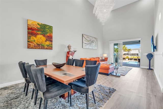 dining area featuring light hardwood / wood-style floors, high vaulted ceiling, and a chandelier