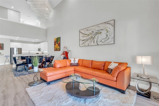 living room with light hardwood / wood-style floors, a high ceiling, and a chandelier