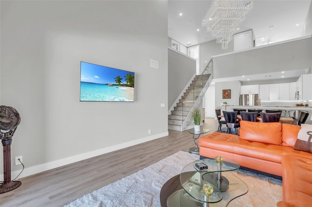 living room featuring a notable chandelier, light hardwood / wood-style floors, and a high ceiling