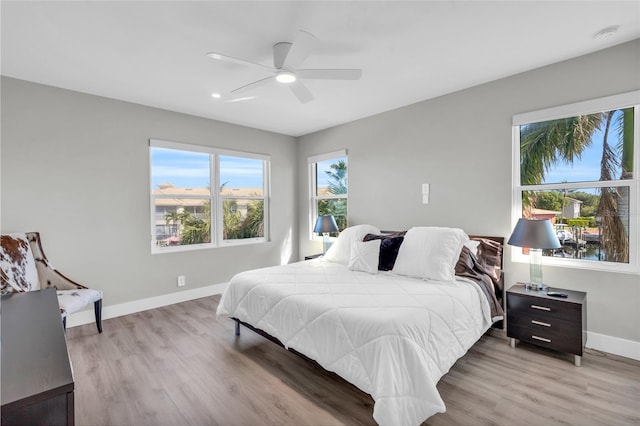 bedroom featuring multiple windows, light hardwood / wood-style floors, and ceiling fan