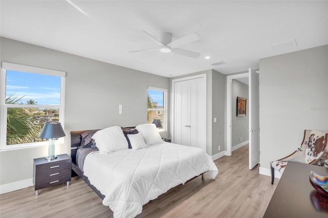 bedroom with multiple windows, a closet, light hardwood / wood-style floors, and ceiling fan