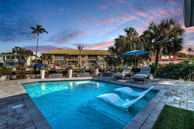 pool at dusk featuring a patio area