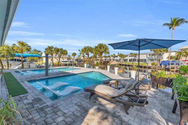 view of pool with pool water feature, a water view, and a patio