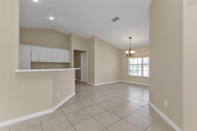 tiled spare room with lofted ceiling and a notable chandelier