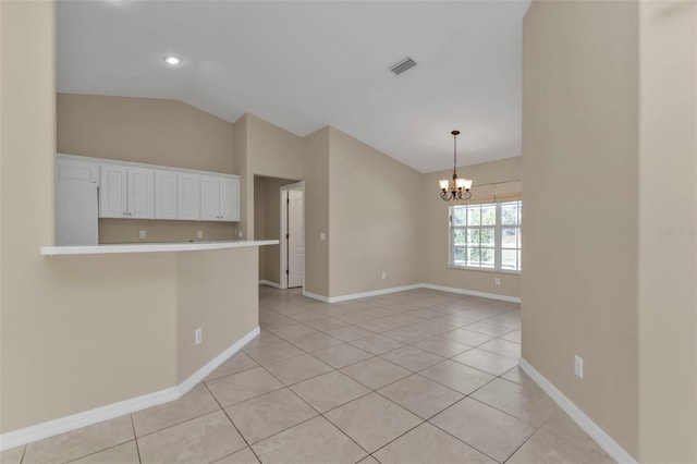 empty room with light tile patterned floors, a chandelier, and vaulted ceiling