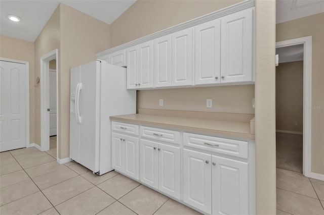 kitchen featuring light tile patterned floors, vaulted ceiling, white cabinetry, and white fridge with ice dispenser