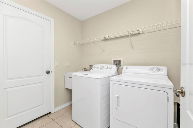 laundry room featuring washer and clothes dryer, light tile patterned flooring, and sink