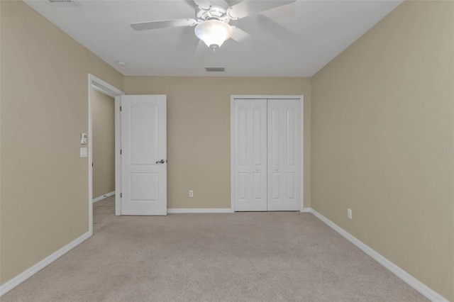 unfurnished bedroom featuring ceiling fan, light colored carpet, and a closet