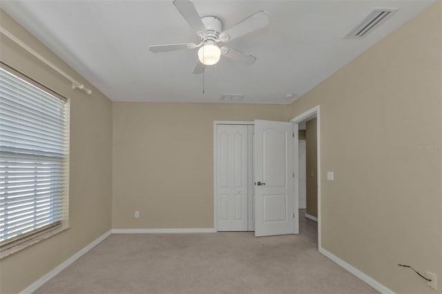 unfurnished bedroom with light carpet, a closet, and ceiling fan