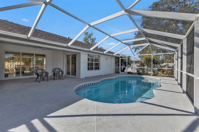 view of pool featuring glass enclosure, a patio area, and ceiling fan