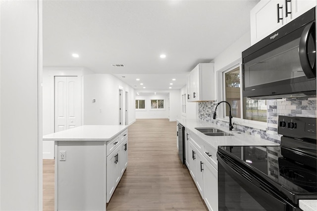 kitchen with black appliances, a center island, white cabinetry, and backsplash