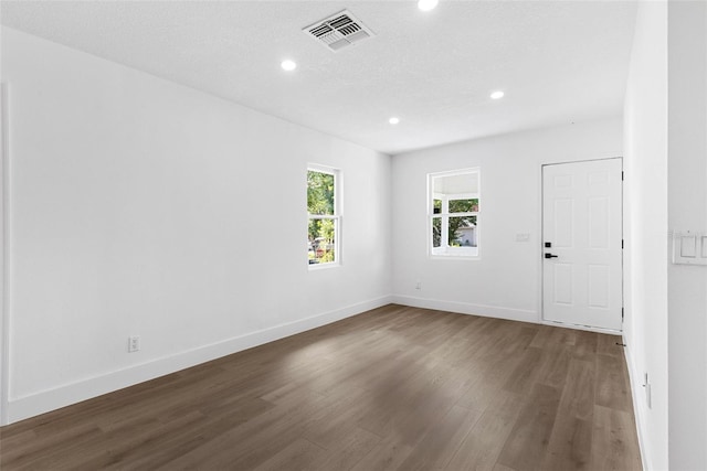 empty room featuring a textured ceiling and dark hardwood / wood-style floors