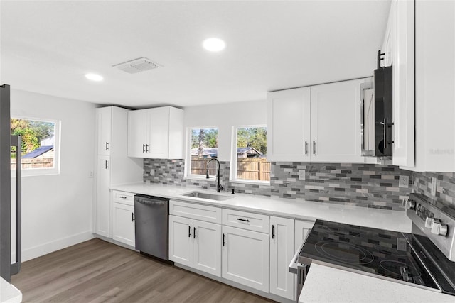 kitchen with hardwood / wood-style floors, sink, white cabinets, and stainless steel appliances