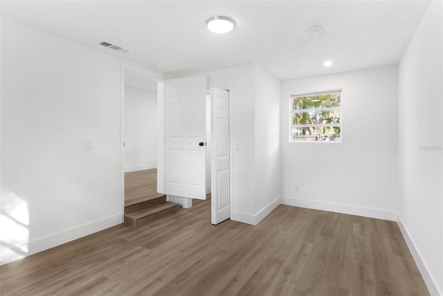 empty room with hardwood / wood-style floors and a textured ceiling