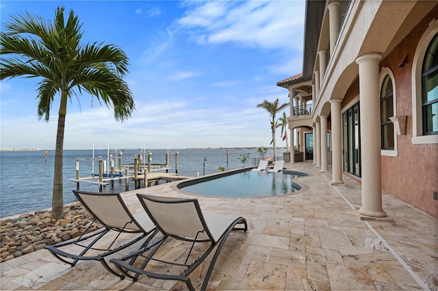 view of swimming pool with a dock, a water view, and a patio