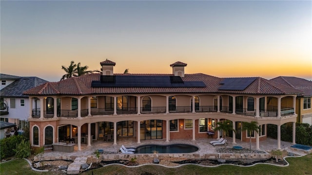 back house at dusk featuring a patio area