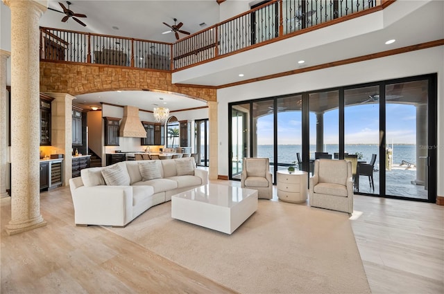 living room featuring a high ceiling, a water view, and ornate columns