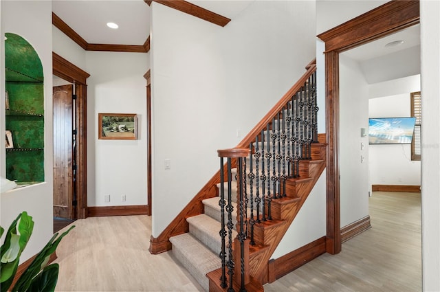 stairs featuring wood-type flooring and ornamental molding