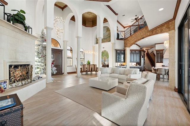 living room with a healthy amount of sunlight, a towering ceiling, decorative columns, and light hardwood / wood-style floors