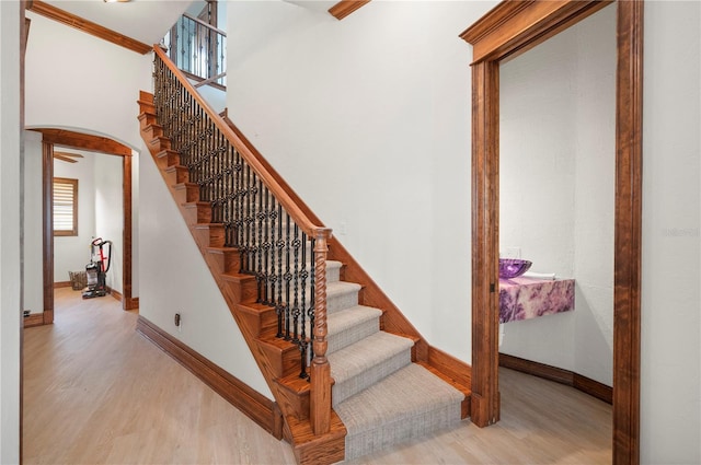 stairs with wood-type flooring and crown molding