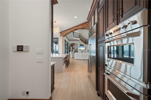 kitchen with plenty of natural light, dark brown cabinets, light wood-type flooring, and hanging light fixtures