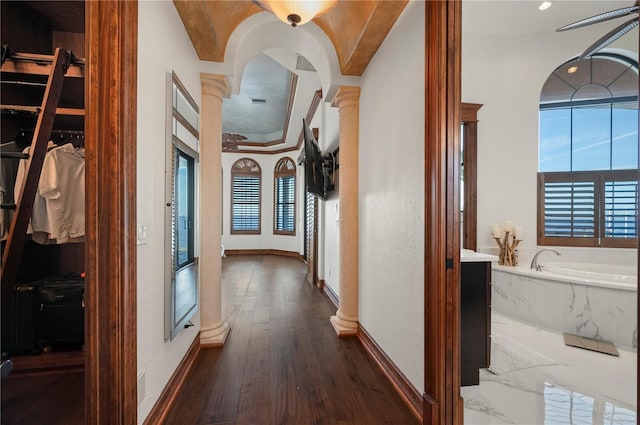 hall featuring dark hardwood / wood-style flooring, plenty of natural light, and ornate columns