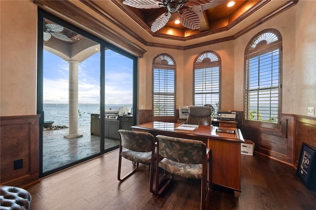 office space with dark wood-type flooring, coffered ceiling, a water view, crown molding, and ceiling fan