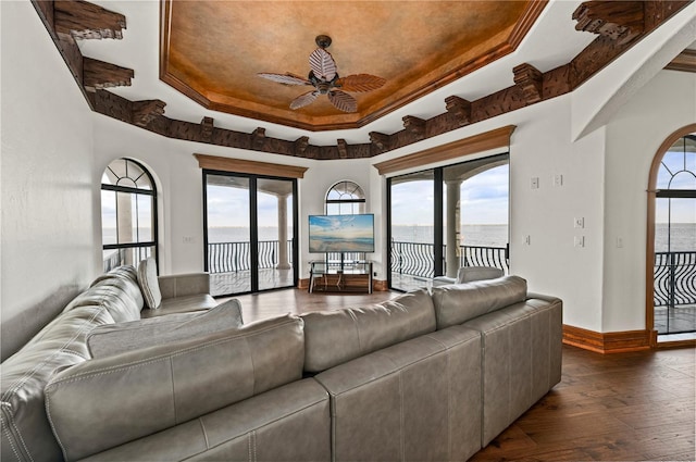 living room featuring a raised ceiling, ceiling fan, and dark hardwood / wood-style floors