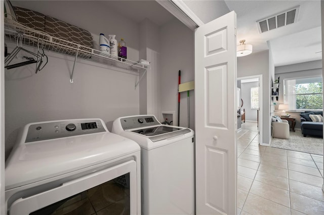 laundry area featuring washer and clothes dryer and light tile patterned flooring