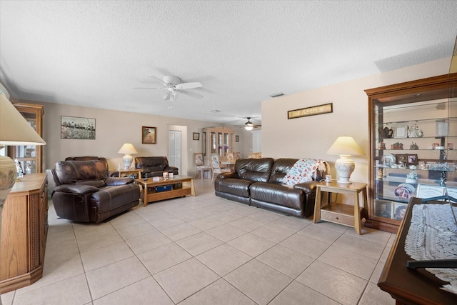 living room featuring ceiling fan, light tile patterned floors, and a textured ceiling