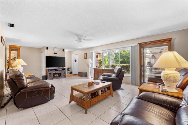 tiled living room with ceiling fan and a textured ceiling