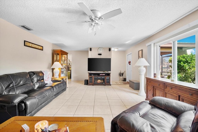 tiled living room with ceiling fan and a textured ceiling