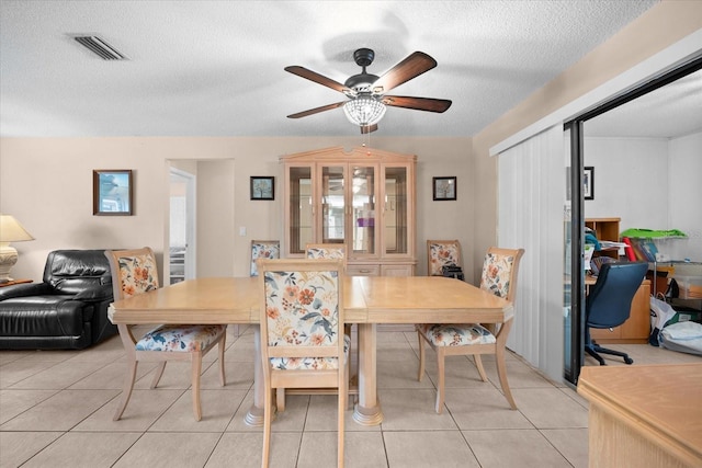 dining space featuring a textured ceiling, ceiling fan, and light tile patterned flooring