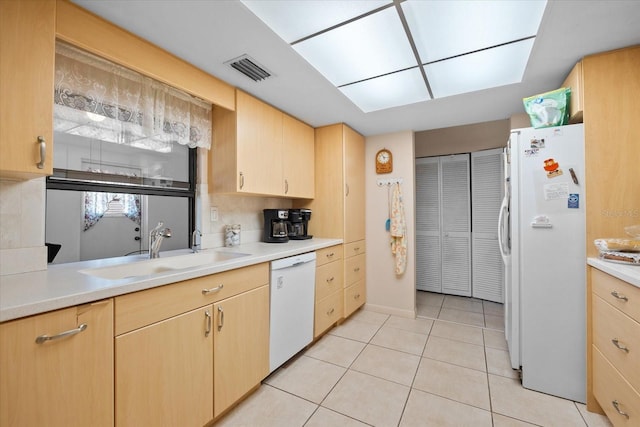 kitchen with backsplash, white appliances, sink, light tile patterned floors, and light brown cabinets