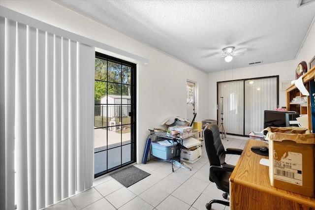 tiled office space featuring ceiling fan and a textured ceiling