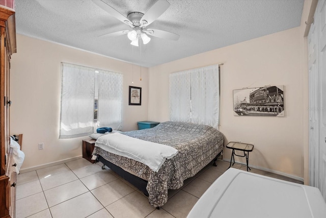 tiled bedroom featuring ceiling fan and a textured ceiling